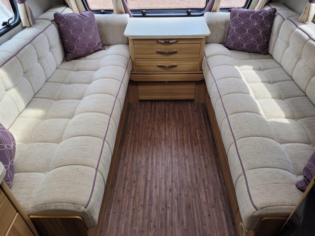 Caravan lounge with beige upholstered seating and purple cushions.