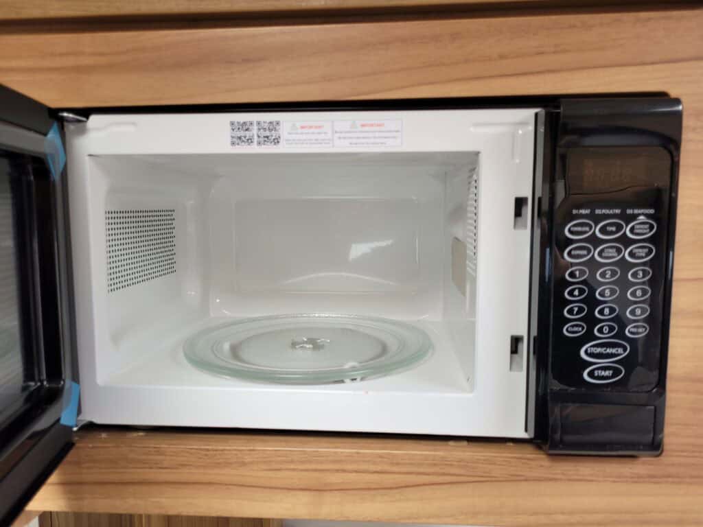 Microwave oven with digital control panel on a wooden surface at Ridgeway Tourers.