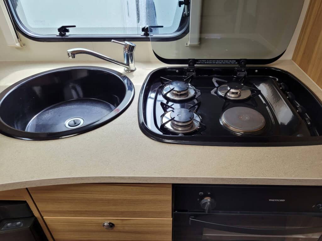 Compact kitchen with sink and gas stove in a campervan.