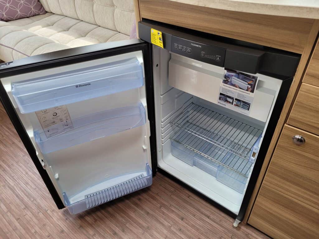 Small kitchen fridge with open door showing interior storage space and shelves.
