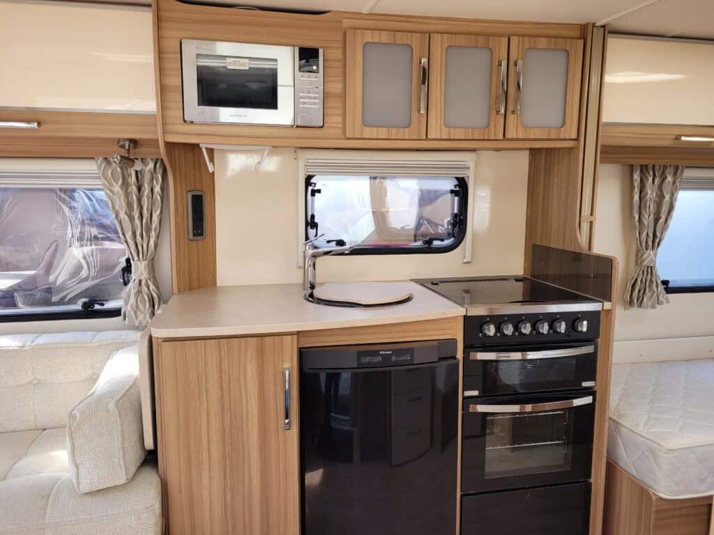 Compact caravan kitchen featuring microwave, oven, and storage cabinets.