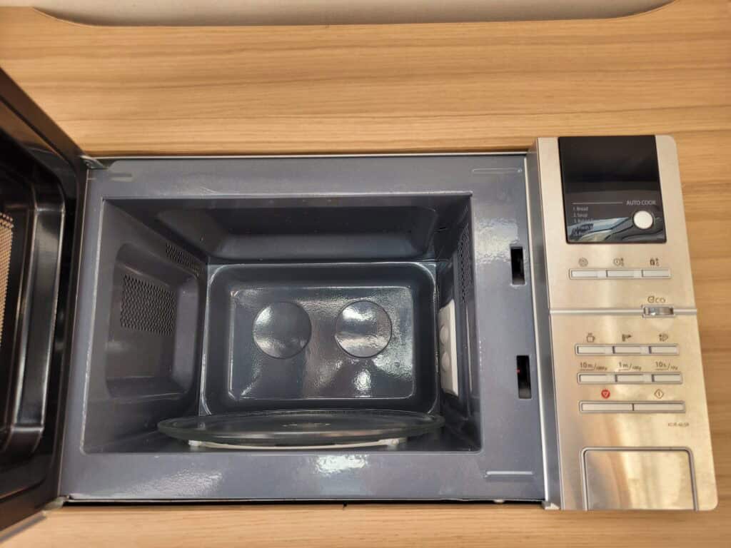 Microwave oven with digital display, control panel, and turntable for quick heating.