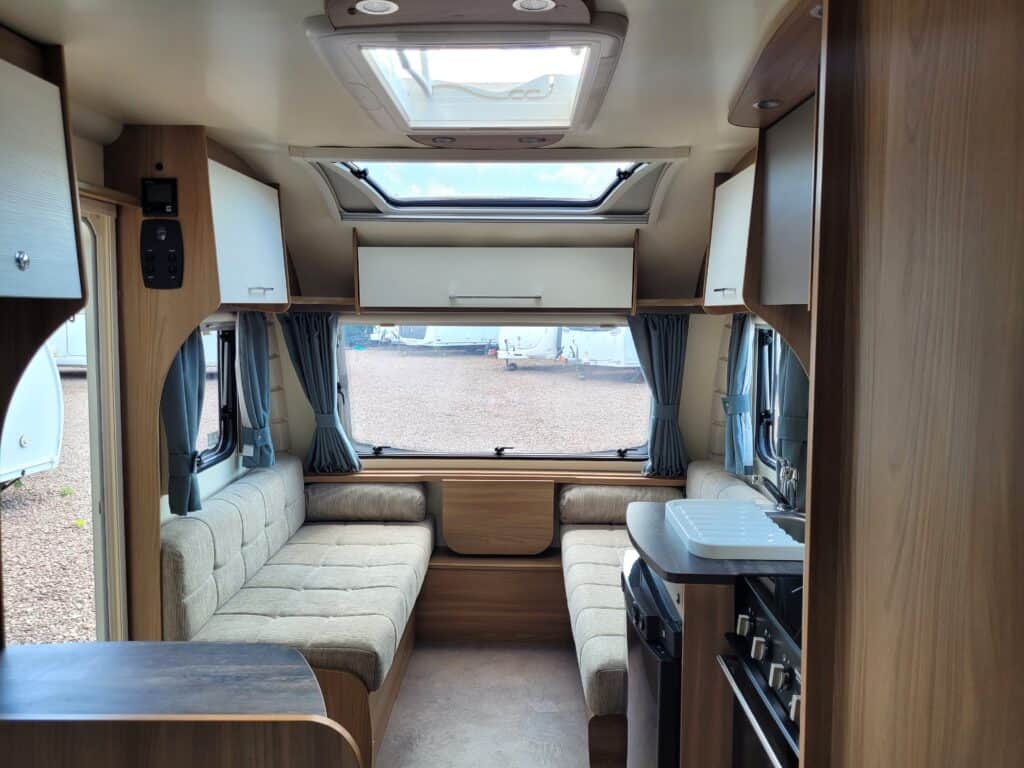 Interior view of a modern caravan with comfortable seating and large windows.