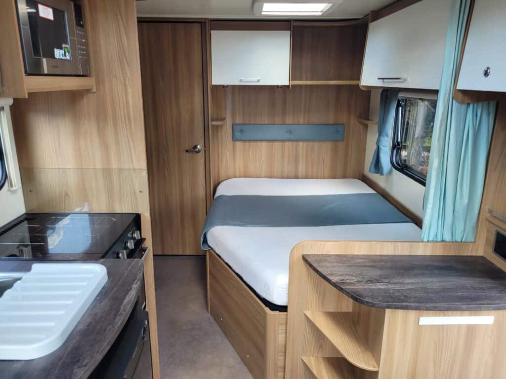 Comfortable caravan bedroom with wooden cabinetry and natural light.