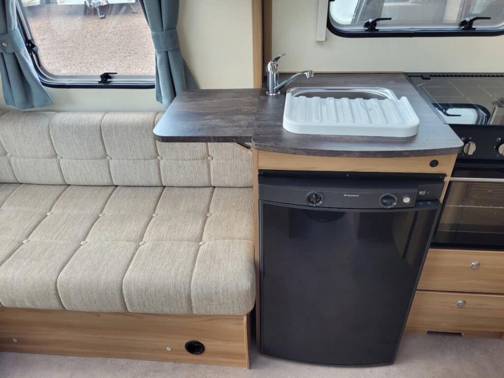 Compact kitchen area inside a Ridgeway Tourers caravan with sink and fridge.