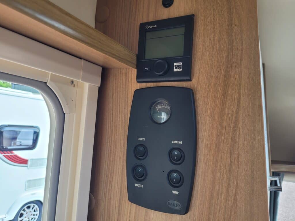 Interior control panel with digital display and switches in a campervan.