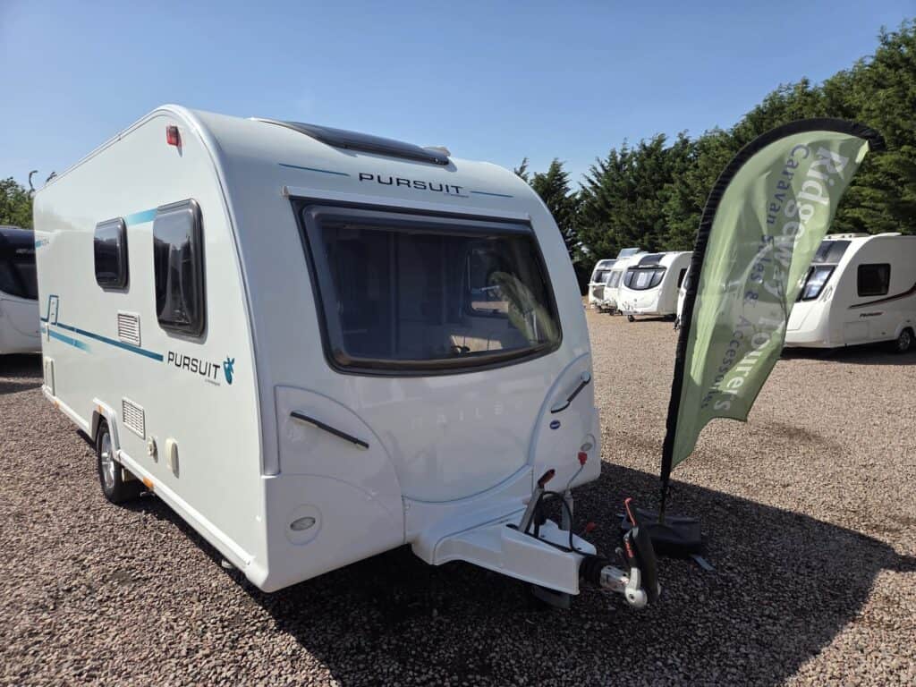 Modern Pursuit caravan displayed at Ridgeway Tourers dealership in a gravel lot.