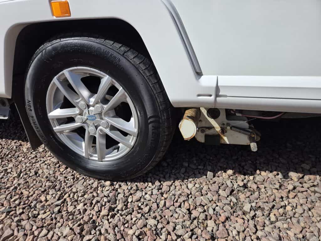 Close-up of the wheel and side of a Ridgeway Tourers electric camper van on gravel.